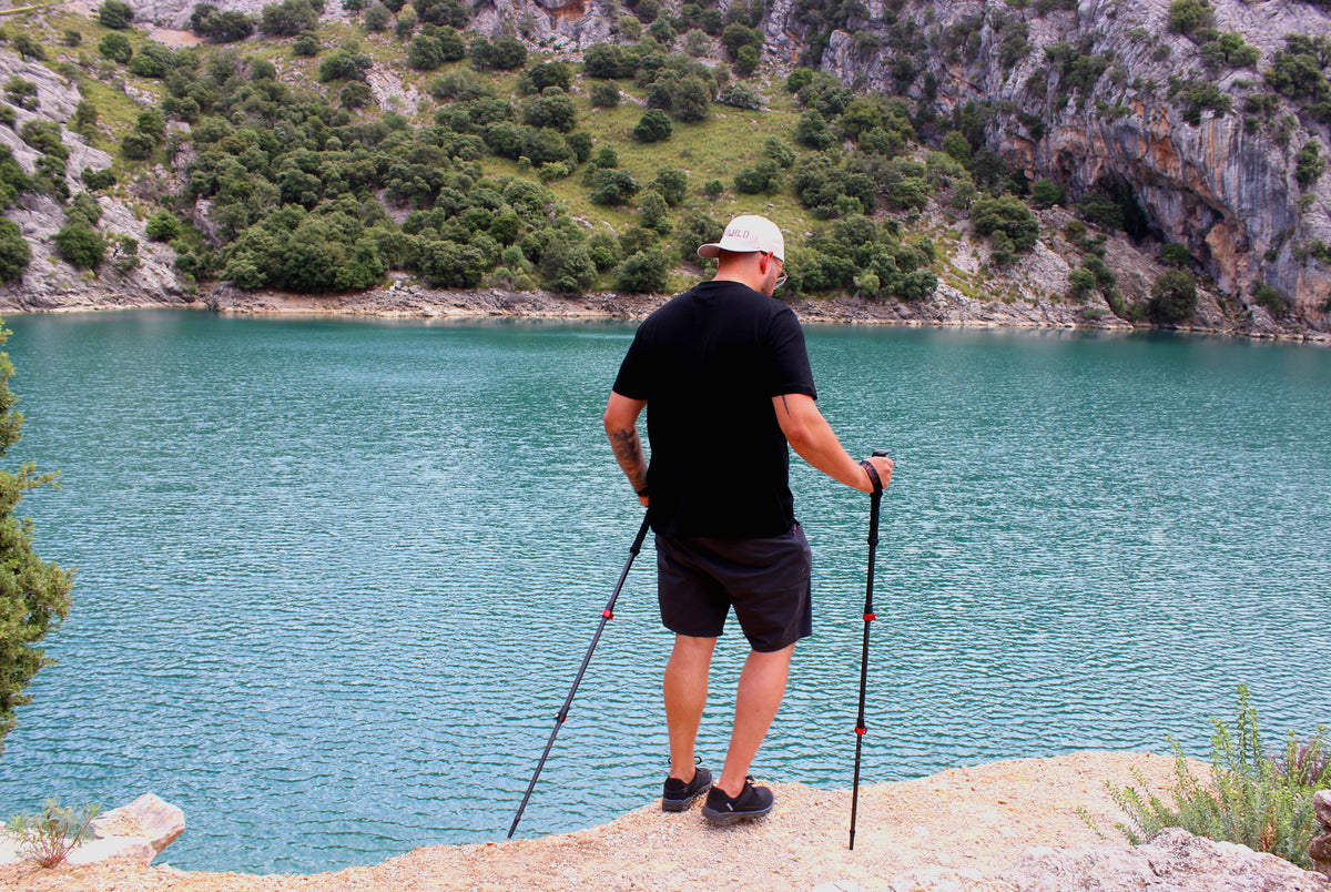 Wanderer mit Rothwild Wanderstöcken Steinbock am Ufer eines Bergsees